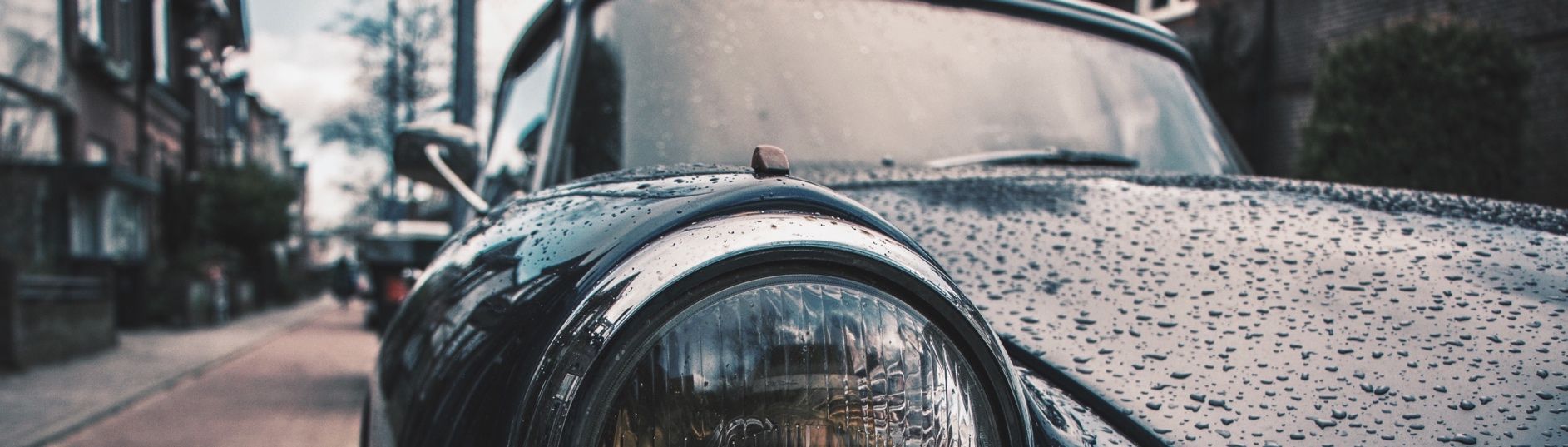 Nahaufnahme eines Oldtimers, von dem Wasser abperlt