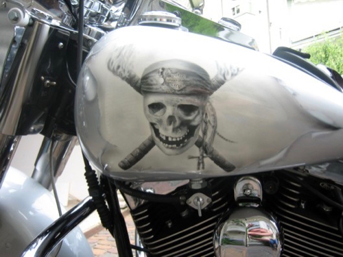 Nahaufnahme eines silbernen Seitenteils eines Motorrads mit einem Airbrush-Bild eines Totenkopfs