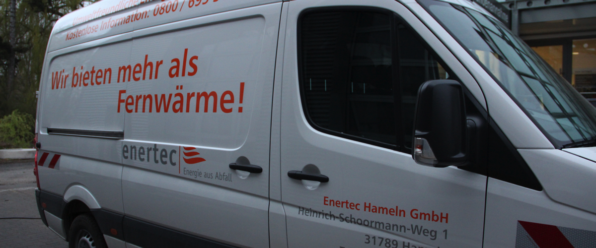 Beschriftung 'Wir bieten mehr als Fernwärme!' in rot/orange auf der hinteren rechten Seite eines weißen Lieferwagens