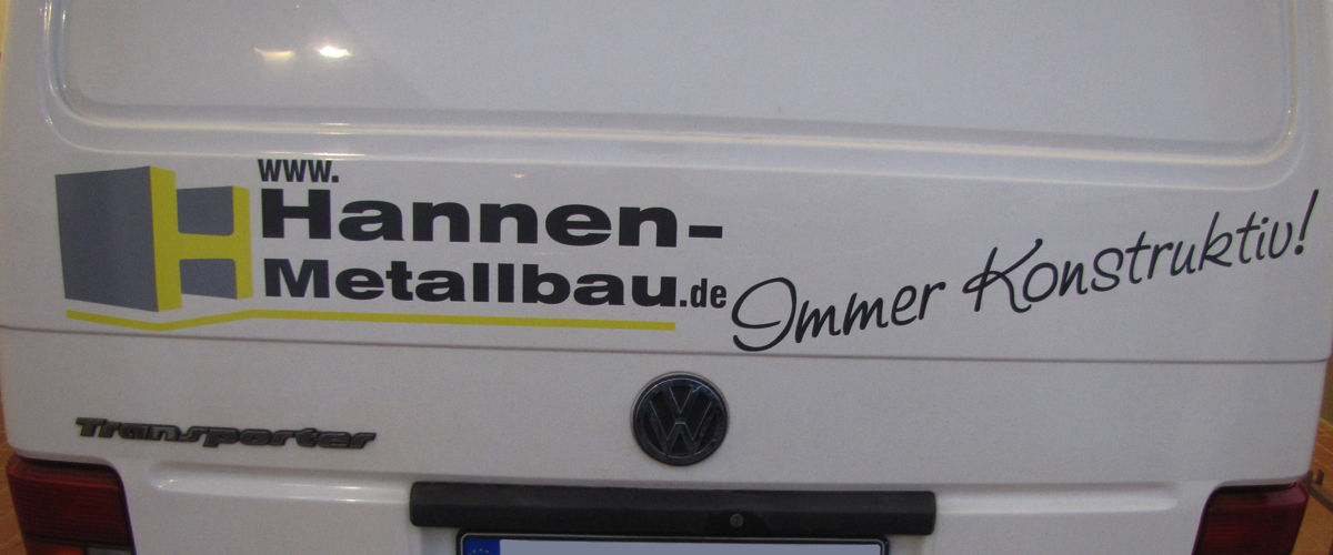 Beschriftung 'hannen-meallbau.de', 'Immer Konstruktiv' auf der Rückseite eines VW Transporters