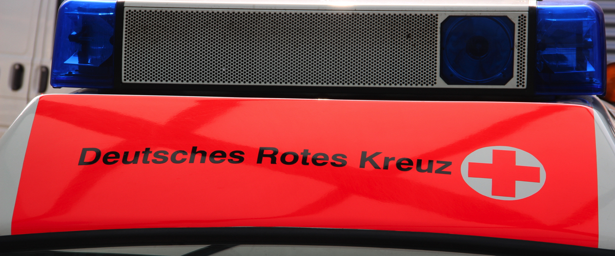 Beschriftung 'Deutsches Rotes Kreuz' mit einem rot Kreuz auf der oberen Front eines Einsatzwagens mit Blaulicht